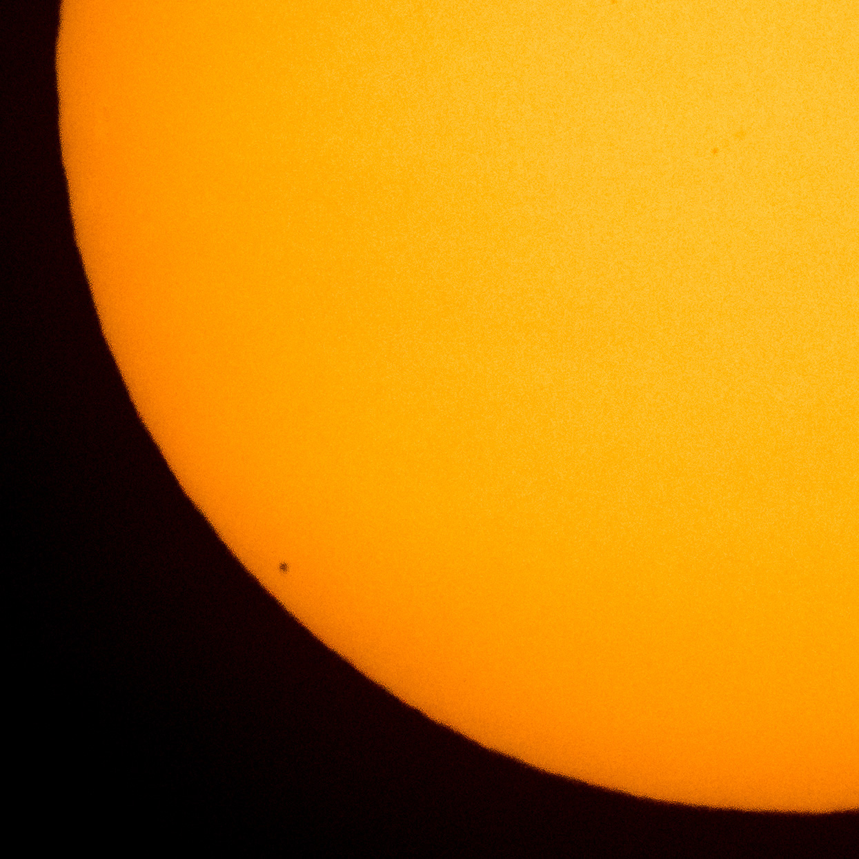 the sun, close up, with tiny planet Mercury visible in front of it