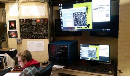 student observing multiple computer monitors in the UA Observatory